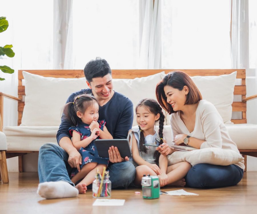 Happy Asian family using tablet, laptop for playing game watching movies, relaxing at home for lifestyle concept